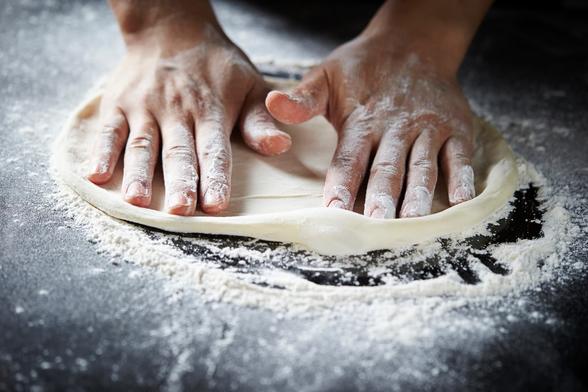 Pizzadeg som formas för hand på mjölat bord hos Pizzapunkten
